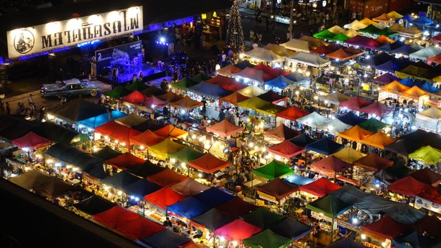 Colorful tents at a vibrant night market full of shoppers and vendors. Ideal for illustrating evening market scenes, city life, urban activities, cultural events, and festive celebrations.