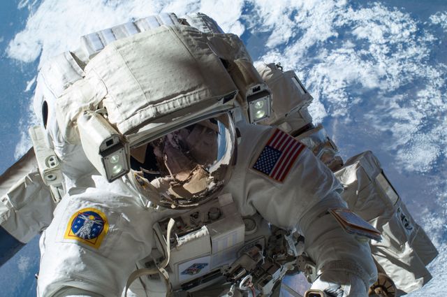 Astronaut on a mission performing a spacewalk outside the International Space Station, with Earth visible in the background. Ideal for articles about space exploration, scientific research, and NASA missions. Use in educational materials, documentaries, and space-themed presentations.