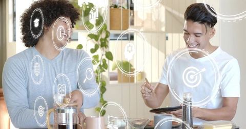 Two men preparing coffee and collaborating over tablet in bright modern kitchen
