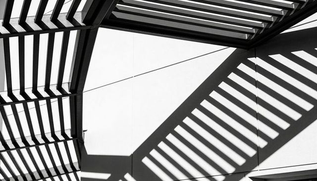 Monochrome architectural shadows creating diagonal stripe pattern from slatted sunshade