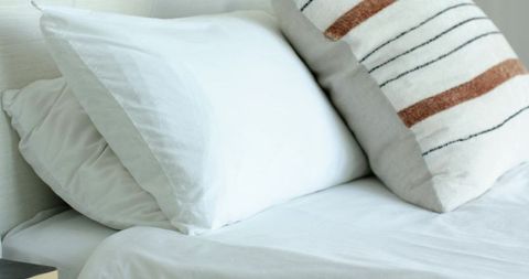 Crisp White Pillows with Textured Striped Throw on Minimalist Neutral Bed