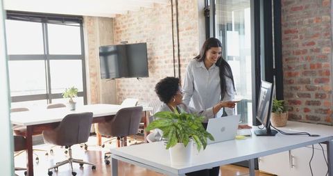 Diverse female coworkers collaborating in open-plan office modern workspace