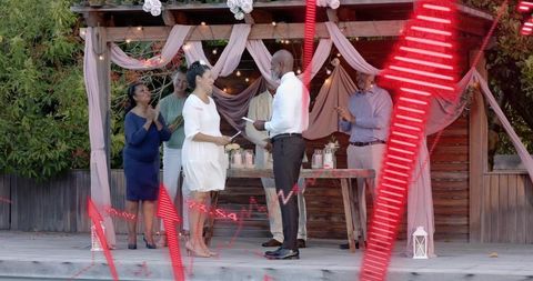Intimate backyard vow exchange under rustic pergola draped with fabrics and lanterns