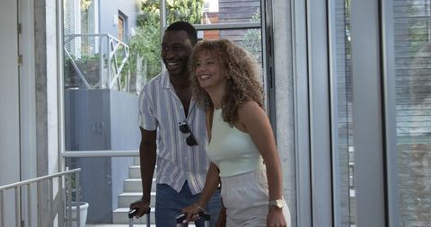Smiling travelers arriving with rolling suitcases in contemporary hotel lobby