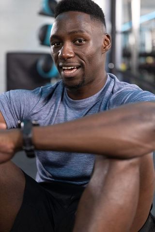 Confident african american man resting after workout wearing blue tee in gym