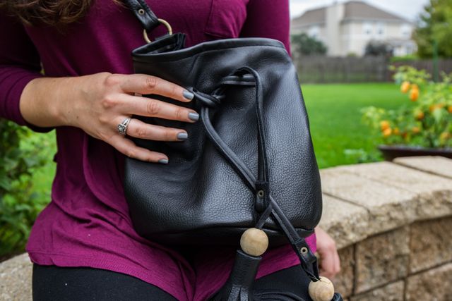 Woman Holding Black Leather Bag in Outdoor Garden - Download Free Stock Photos Pikwizard.com
