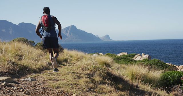 African american man cross country running in countryside by the coast. fitness training and healthy outdoor lifestyle.