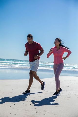 Energetic Couple Jogging Along Sunny Beach for Fitness