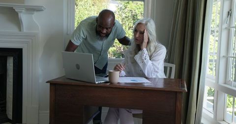 Elderly Couple Discussing Finances at Home with Laptop