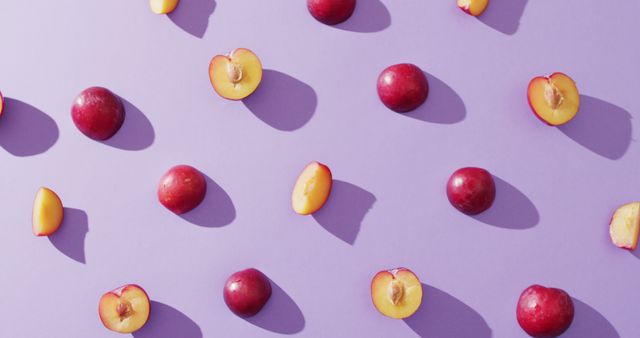 Image of fresh plums and plum cuts lying on lilac surface. food, fruits, freshens, taste and flavour concept.