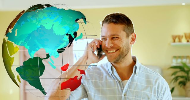 A smiling man is talking on a phone indoors with a globe graphic overlay, suggesting global communications. Useful for representing modern business, international connectivity, technology, and cheerful communication interactions.