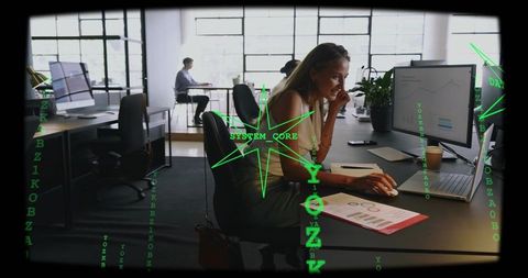 Woman working on laptop with data charts and cybersecurity code overlay in modern open-plan office