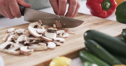Chopping Fresh Mushrooms on Wooden Cutting Board in Kitchen