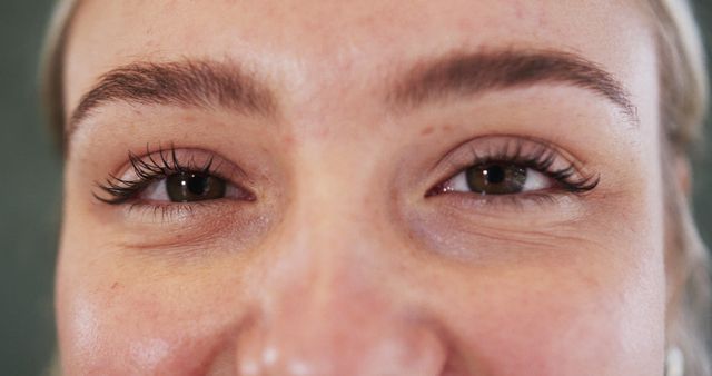 This close-up captures a woman's beautiful eyes and thick eyebrows, highlighting natural makeup and healthy skin. Ideal for beauty and skincare advertisements, cosmetics promotions, and editorial uses that focus on facial features and natural beauty enhancements.