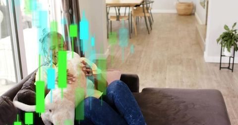 Senior woman cuddling dog on sofa with candlestick chart overlay representing home trading