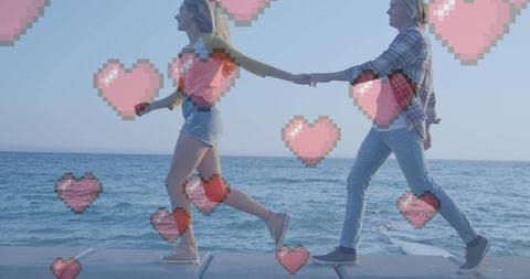 Couple walk holding hands with heart icons by the sea