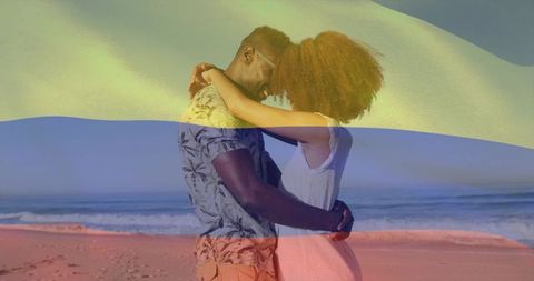 Sunlit couple embracing on beach with colorful light bands over ocean horizon