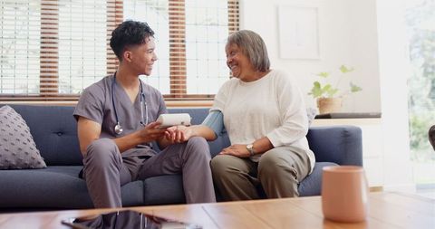 Male Nurse Assisting Senior Woman with Blood Pressure Measurement at Home
