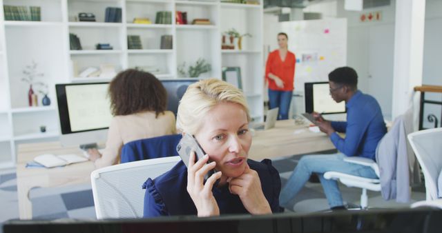 Businesswoman Talking on Phone in Modern Office with Colleagues Working - Download Free Stock Images Pikwizard.com