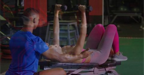 Personal trainer assisting client in bench press exercise at gym