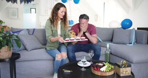 Man Celebrating Birthday with Woman Holding Cupcakes at Home