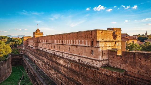 Ancient brick fortress with deep moat and tower overlooking sunlit city skyline at dusk