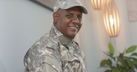 Confident military man in camouflage uniform indoors
