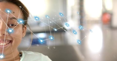 Smiling woman wearing light top and necklace, blue network overlay in bright lobby