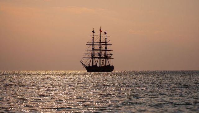 Silhouette of tall ship at sea during serene sunset