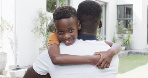 Father and Son Hugging with Joyful Smiles Outdoors