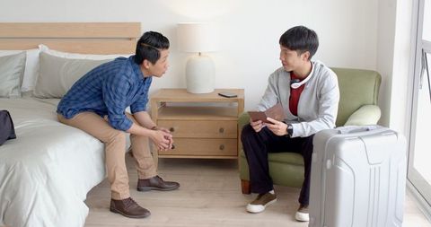Two Friends Shaking Hands in Cozy Bedroom Setting Meeting Before Travel
