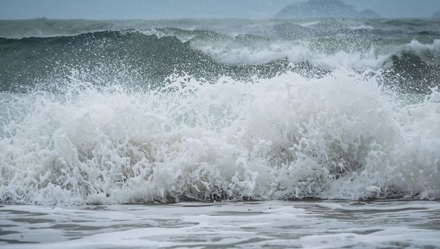 Crashing ocean waves surging onto wet sandy shore with foaming white surf spray