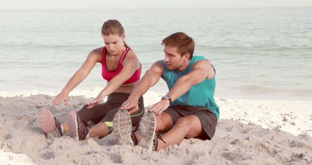 A young Caucasian man and woman are stretching on a sandy beach, with copy space - Download Free Stock Photos Pikwizard.com
