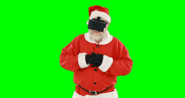 Santa Claus is immersing himself in a virtual reality experience with a VR headset while standing against a green screen background. This image can be used for advertising Christmas promotions, modern holiday greeting cards, technology and festive-themed marketing campaigns, or illustrating a blend of traditional holiday icons with modern technology.