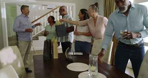 Senior Friends Celebrating at Home with Drinks and Gifts Exchange