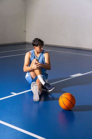 Teen Basketball Player Stretching on Indoor Court