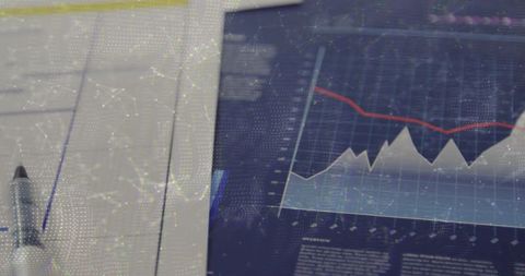 Tablet displaying downward trend chart with analytics overlay on office desk, forms, pen