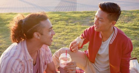 Diverse Gay Couple Enjoying Picnic at Sunset by the Sea