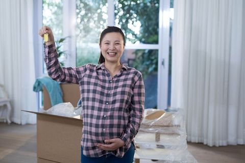 Pregnant Woman Holding House Keys in Bright Living Room