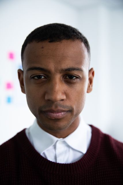 Portrait of a young African American man with short hair and black eyes looking straight to camera in the office of a creative business.