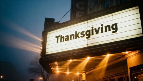 Vintage theater marquee glowing thanksgiving sign at foggy dusk with warm bulb lights