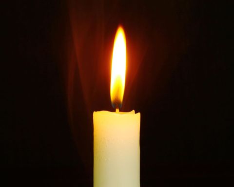 Wax Candle Burning Against Dark Background