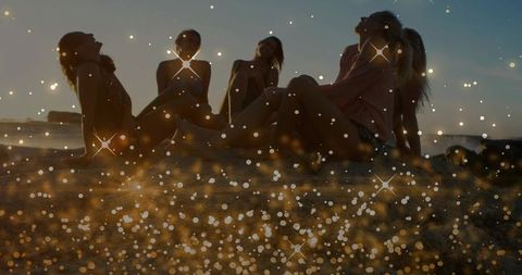 Sunset silhouettes of five women on beach with golden bokeh sparkle, summer relaxation