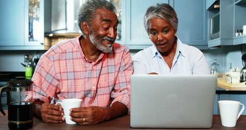 Senior Couple Using Laptop with Coffee at Home Kitchen Table - Download Free Stock Images Pikwizard.com