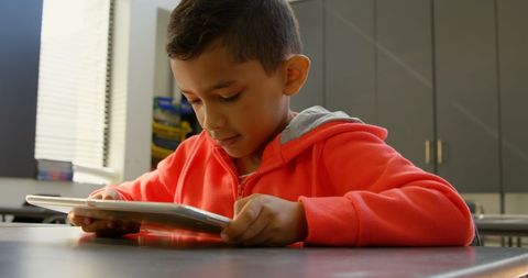 Focused young boy engaging with digital tablet in classroom