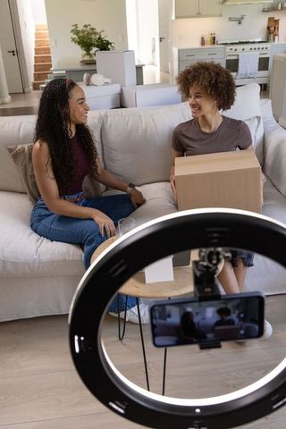 African american influencers unboxing and filming with ring light in modern living room
