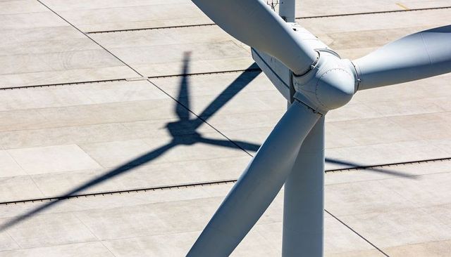 Wind turbine rotor hub and three blade roots casting crisp shadow on concrete service pad