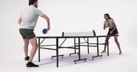 Friends Engaging in Energetic Table Tennis Game