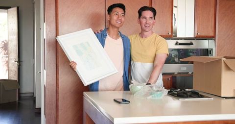 Happy Male Couple Unpacking in Bright Modern Kitchen