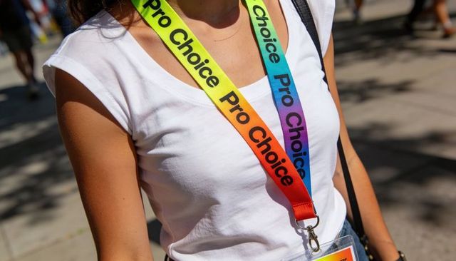 Young woman wearing rainbow pro choice lanyards at outdoor rally